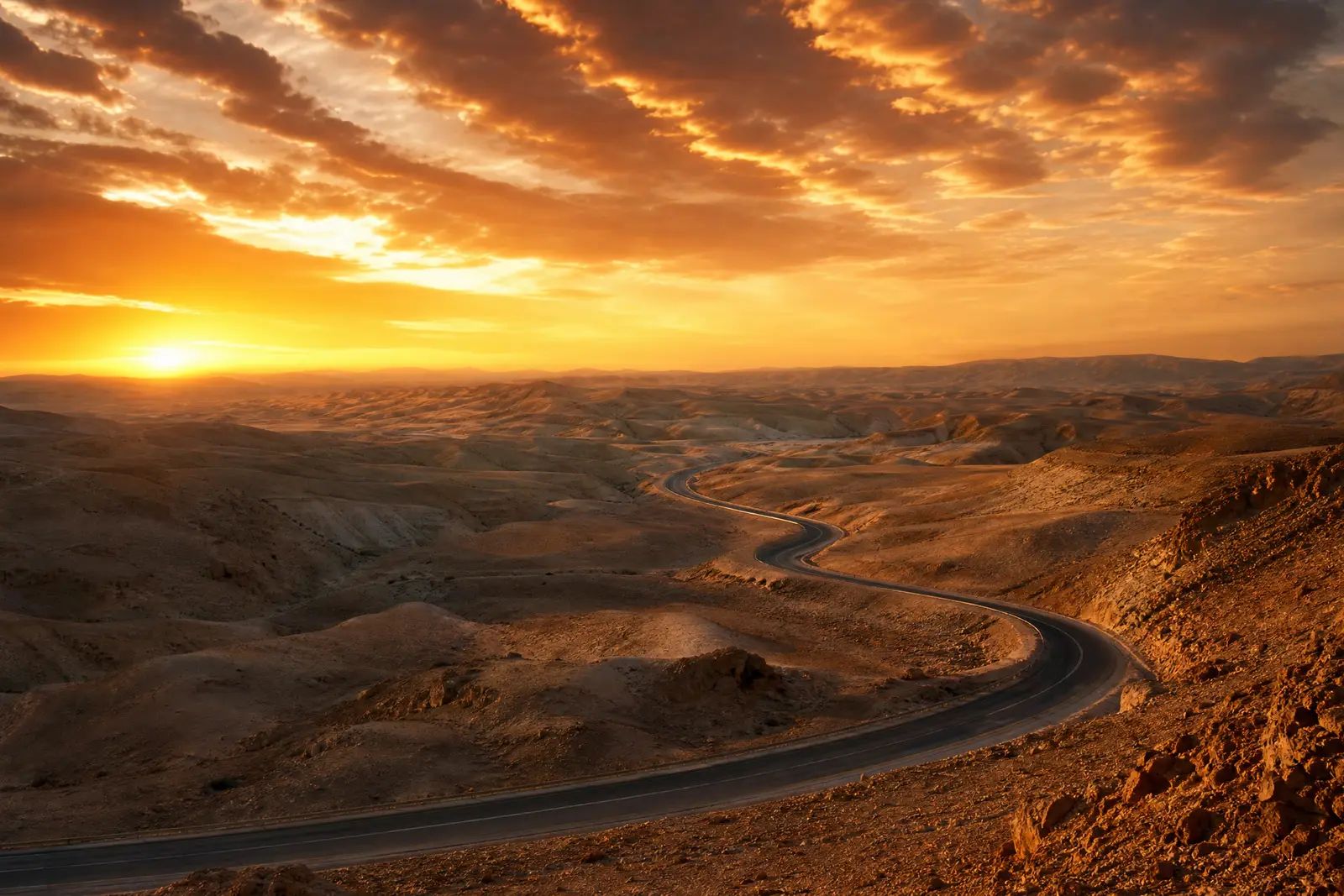 A winding road through the Negev desert at sunset