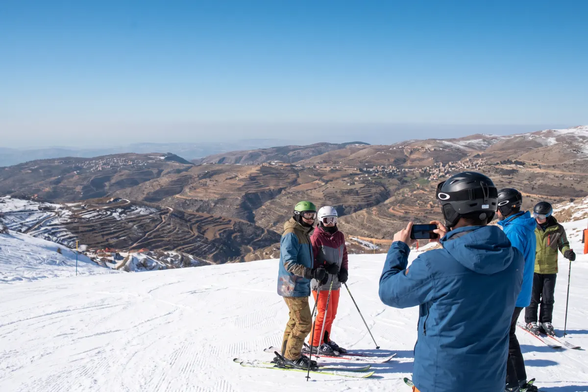 Skieurs sur les pentes enneigées du mont Hermon, l'un photographie avec son smartphone